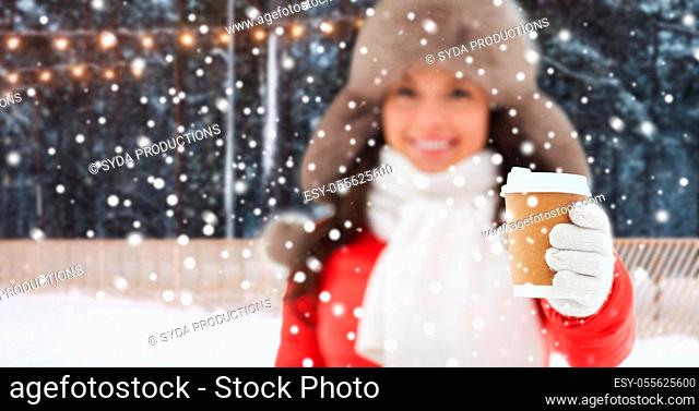 happy woman with coffee cup over winter ice rink
