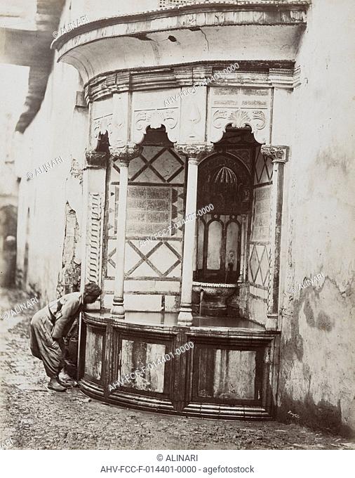 A man drinking from a corner fountain, on a street in Damascus, Syria, shot 1865 ca. by Bonfils, Félix