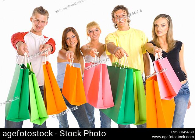 Small group of smiling teenagers. Holding and giving shopping bags. Looking at camera. White background, front view