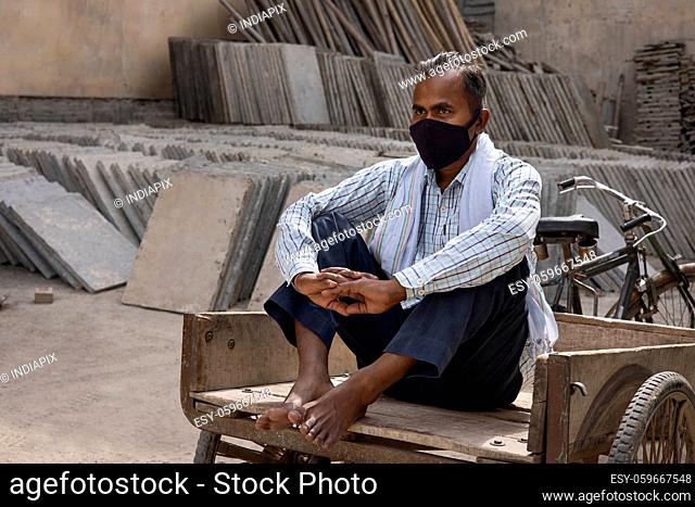 A DAILY WAGE LABOURER RESTING ON CART AFTER WORK