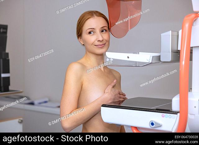 Young woman getting medical test to prevent breast cancer and promoting awareness to get early mammograms in modern clinic