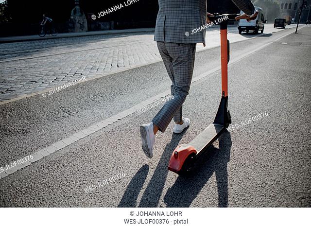 Businessman walking with e-scooter in the city