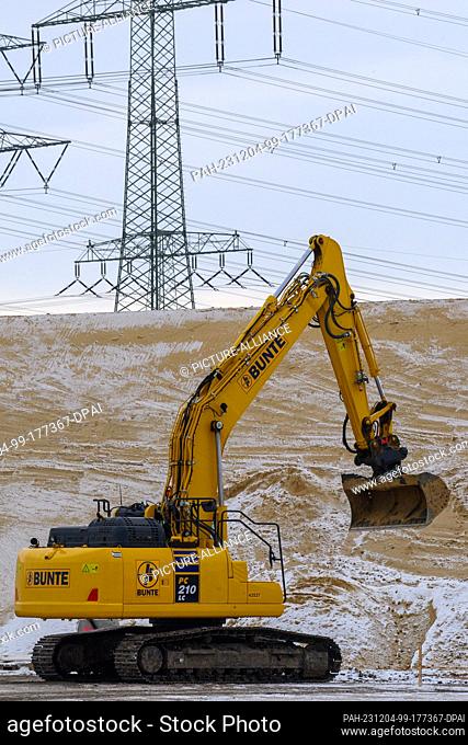 04 December 2023, Saxony-Anhalt, Niedere Börde: An excavator rolls over the construction site for the next section of the A14 north of Magdeburg