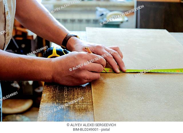Hands of Caucasian man using pencil and measuring tape
