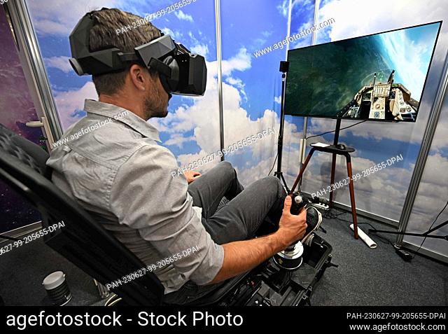 27 June 2023, Bavaria, Munich: A trade fair visitor tests the flight in a fighter aircraft F16 with a flight simulator of the company Benthor at Automatica 2023...