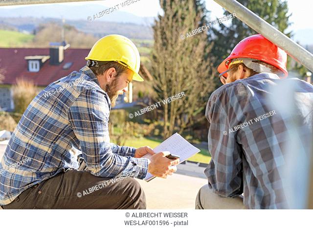Two craftsmen looking at notes in construction site