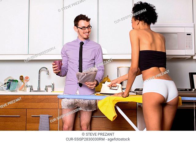 Young couple in kitchen, woman ironing in underwear