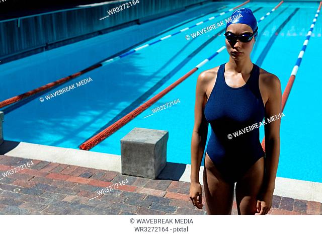 Young female swimmer with swim goggle standing at swimming pool