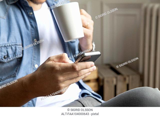 Man catching up with emails while having morning coffee