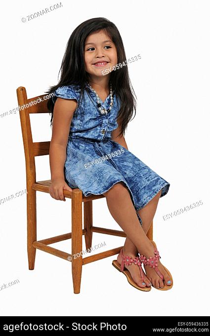 Beautiful and young stylish little girl sitting in a chair