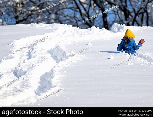 03 December 2023, Bavaria, Munich: A child runs through the snow in the Olympic Park. Snow and ice have caused chaos on the roads and on the railroads in...