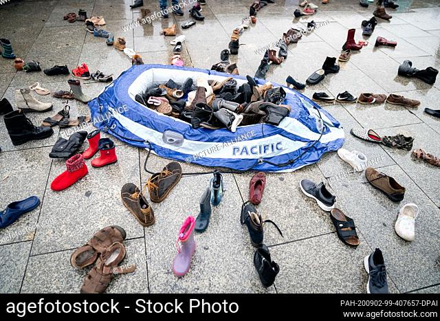 02 September 2020, Berlin: A rubber dinghy and around 200 pairs of shoes lie in the station forecourt as an installation for a vigil for the 5th anniversary of...