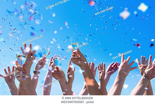 People exulting, Arms raised with champagne glasses, confetti