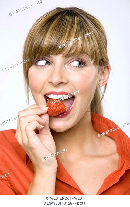 Young woman eating strawberry, close-up