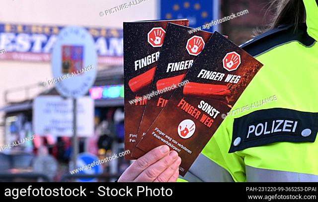 20 December 2023, Saxony, Bärenstein: A federal policewoman shows flyers with the inscription ""Hands off, otherwise hands off"" on how to handle fireworks