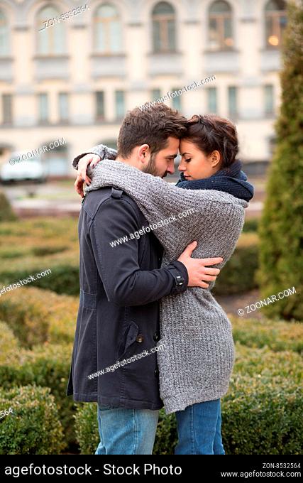 Portrait of happy couple hugging in the autumn park and standing face to face. Beautiful people in love