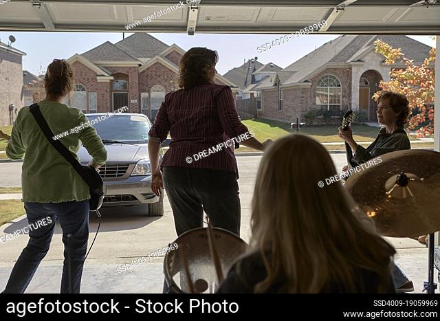 Garage band composed of middle aged women, practicing in residential garage of suburban home