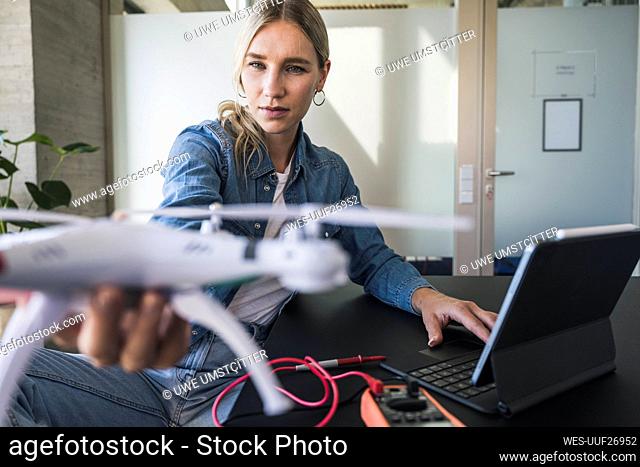 Woman examining drone using tablet PC at office