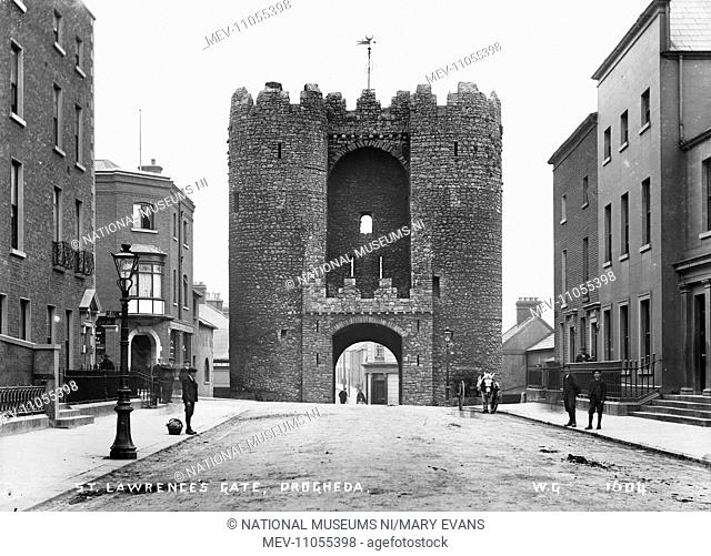 St. Lawrence's Gate, Drogheda - a view up a street to the stone gate tower, there are people and a horse vehicle. (Location: Republic of Ireland: County Louth:...