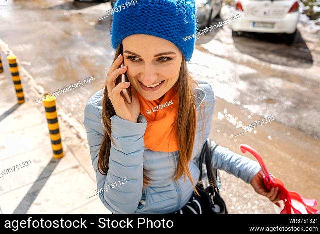 Woman using her phone walking thru mud and thawing snow in pre-spring