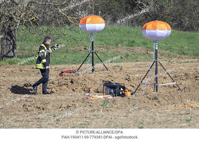 11 April 2019, Hessen, Wiesbaden: A firefighter inspects the location of a world war bomb on a field near Bierstadt. The dud is to be defused in the evening