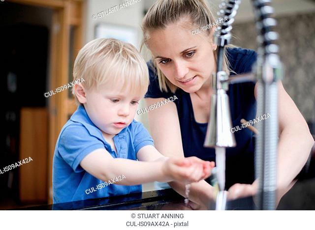 Mother helping son wash his hands