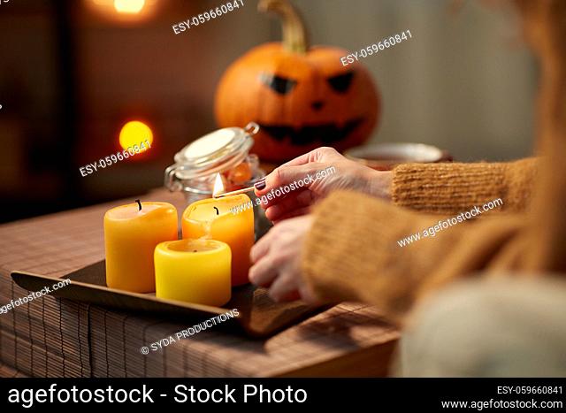 hand with match lighting candle on halloween
