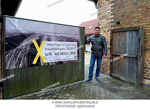Ingo Schuster standing at the entrance of his four-sided courtyard in Rohne, Germany, 8 April 2015. Next to a sign which reads 'Unsere Region ist durch...