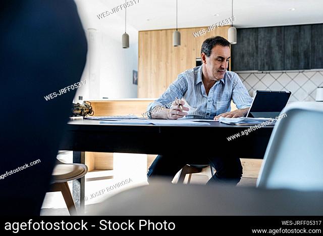 Musician e-learning through tablet PC sitting in kitchen at table