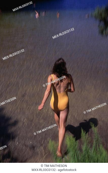 Woman walking into water, Summerland, BC, Canada