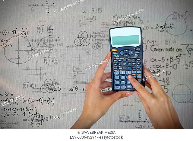 Composite image of cropped hands of businesswoman using calculator