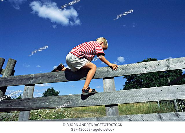 Boy climbing over a fence