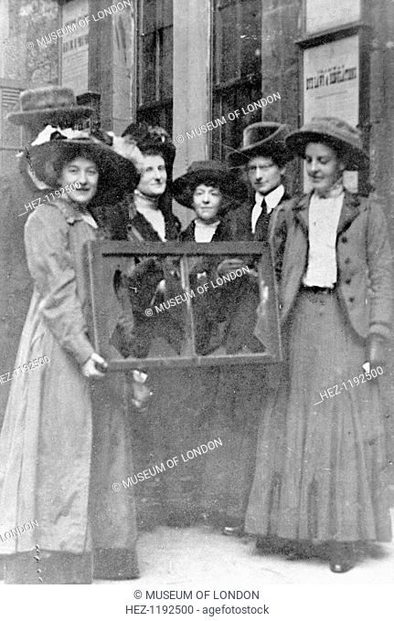 Five suffragettes holding a broken window in its frame, 1912. Adela Pankhurst is on the far left. From 1911, window smashing as executed by Mary Leigh and Edith...