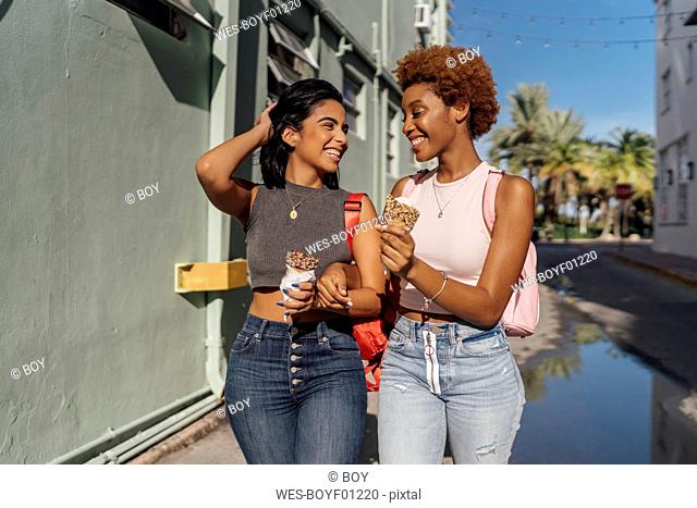 USA, Florida, Miami Beach, two happy female friends with ice cream cones in the city