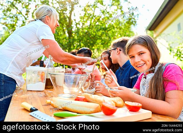 Lehrerin und Kinder zusammen im Kochkurs für gesunde Ernährung im Sommercamp