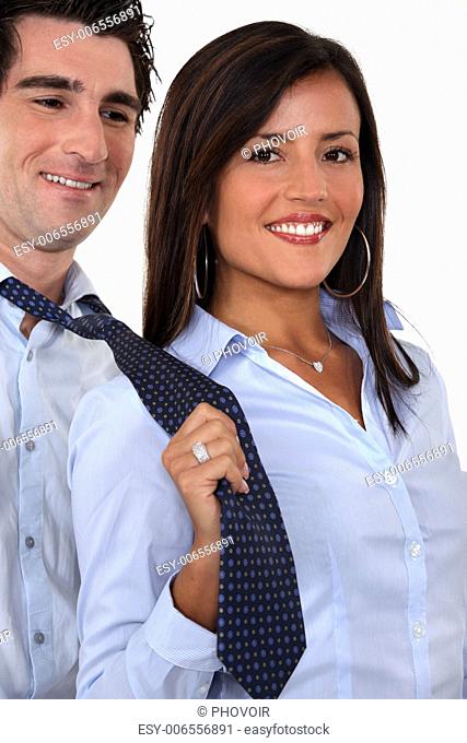 A businesswoman pulling her colleague by the tie