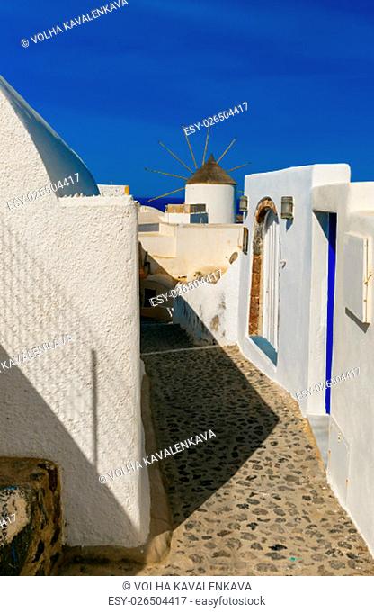 Picturesque view of empty streer, white and blue houses and windmill in Oia or Ia, island Santorini, Greece