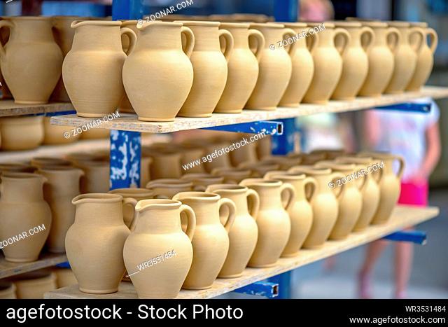 Ceramic dishware arranged on shelf in pottery workshop