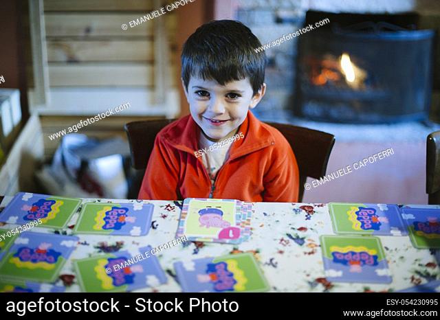 Portrait of little boy sitting at the table while making grimaces