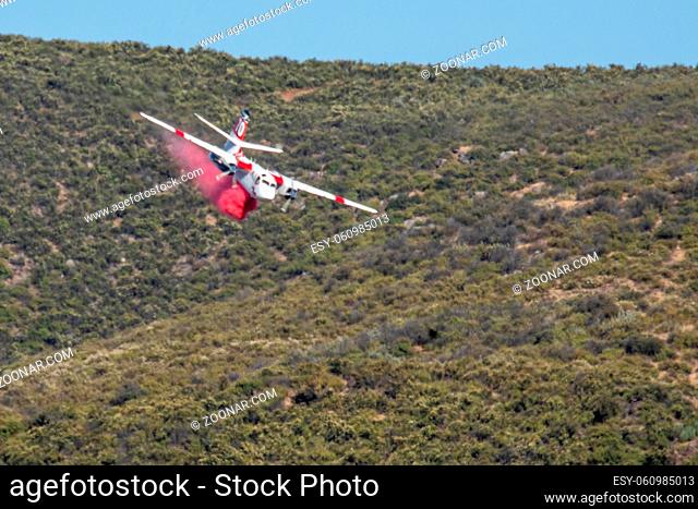 Winchester, CA USA - June 14, 2020: Cal Fire aircraft drops fire retardant on a dry hilltop wildfire near Winchester, California