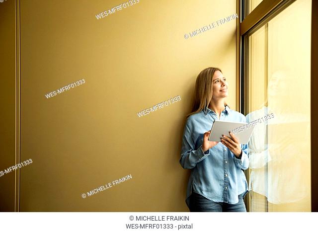 Businesswoman with tablet looking out of window