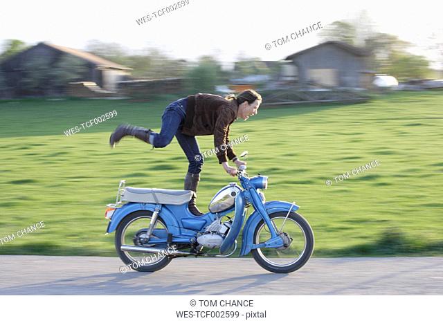 Germany, Bavaria, Mature woman riding old moped of 1960s
