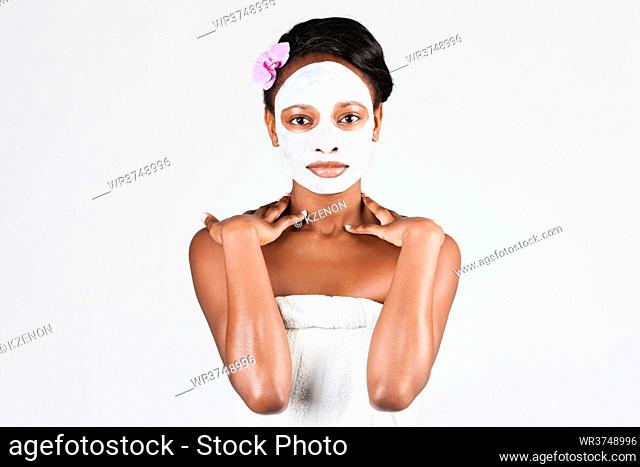 Young African woman in Studio doing body care with refreshing facial mask for young and beautiful skin and relaxation