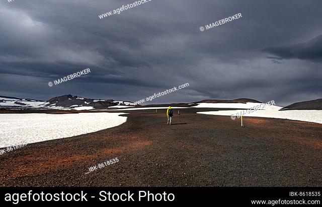Hikers in snow-covered volcanic landscape with volcanic sand and petrified lava, crater of Askja volcano, Icelandic highlands, Iceland, Europe