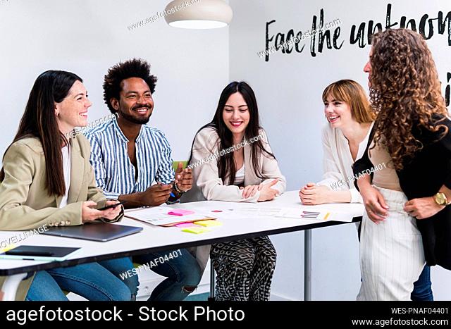 Happy business team talking at table in office