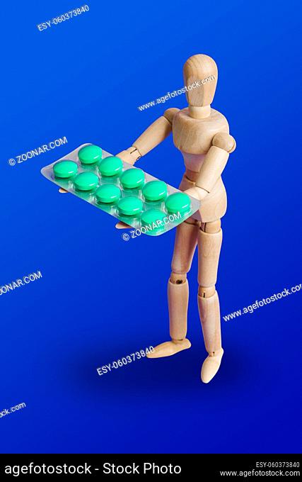 Wooden toy figure with pills on blue background