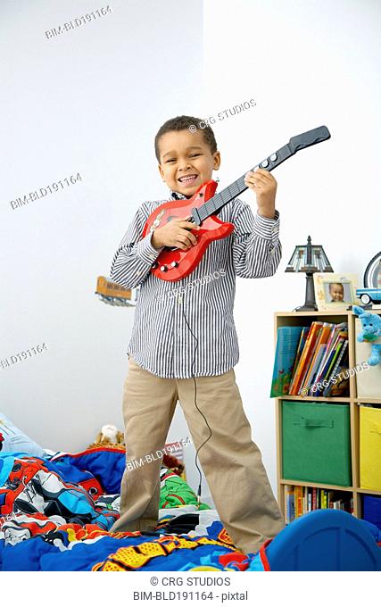 Mixed race boy playing toy guitar