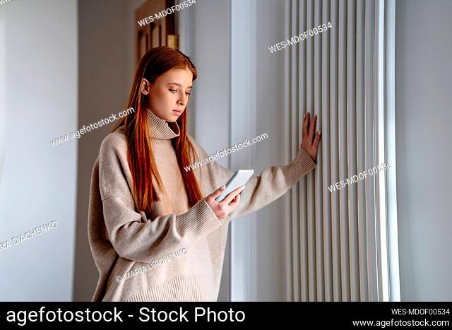 Teenage girl using smart phone touching smart phone at home