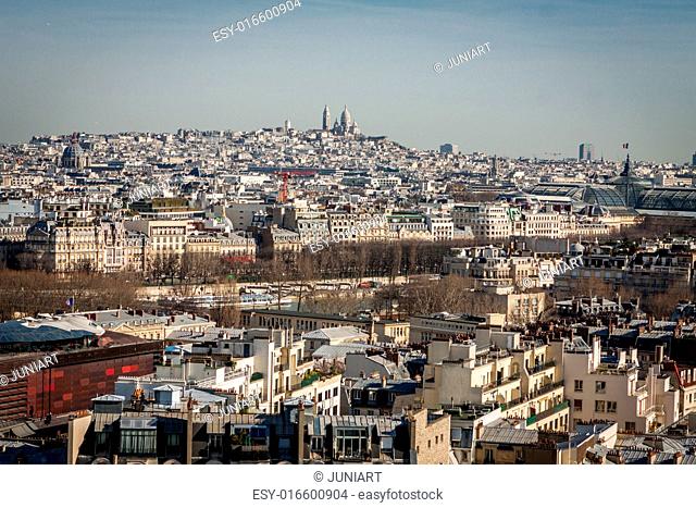 View over the rooftops of Paris, France with its streets of historical buildings to a distant skyline under a blue sky, travel concept
