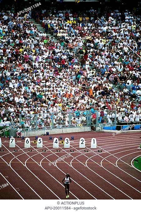 Spectators at a large track meet look along the 100 meters track lanes